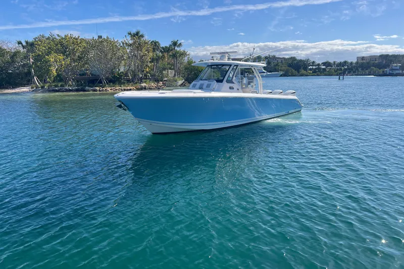 Slide: The Image of 2019 Pursuit S 368 Sport boat on clear blue water, sunny day, lush shoreline. - 6