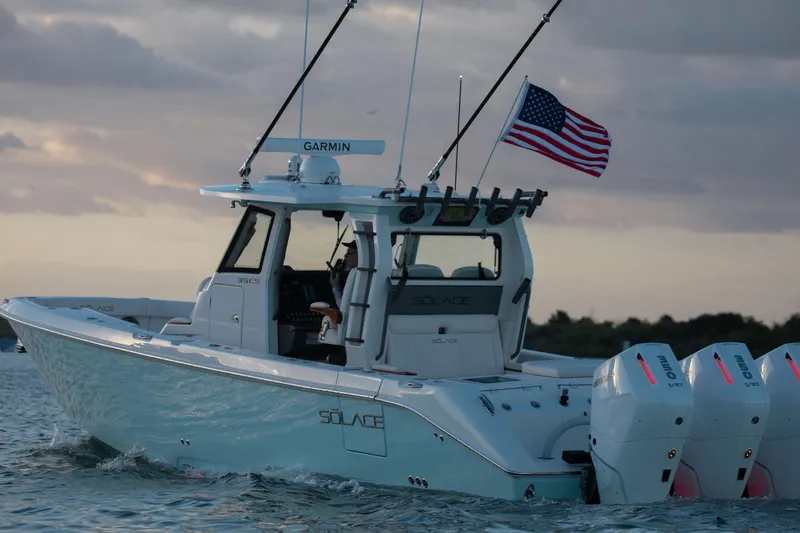 Slide: The Image of 2026 Solace 35 CS boat with American flag, cruising on water at sunset. - 2