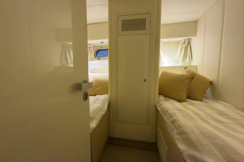 Slide: The Image of Cozy twin cabin in 1997 Magnum 56 yacht with beige decor and porthole window. - 42