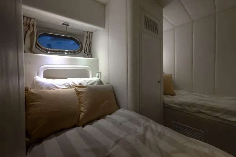 Slide: The Image of Cozy cabin interior of 1997 Magnum 56 yacht with twin beds and porthole window. - 52