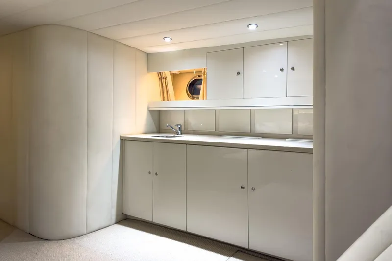 Slide: The Image of Luxurious yacht interior kitchen with sleek white cabinets, modern lighting, and a small window. Magnum 56, 1997. - 54
