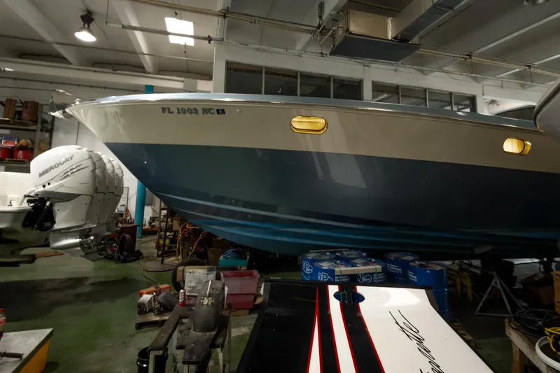 Slide: The Image of 1997 Magnum 56 boat in a garage, featuring a blue hull and Mercury engines. - 64