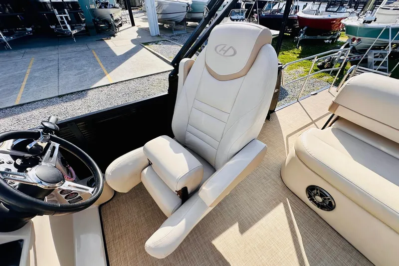 Slide: The Image of Captain's seat and steering wheel of 2019 Harris Cruiser 250 boat, docked with other vessels. - 14