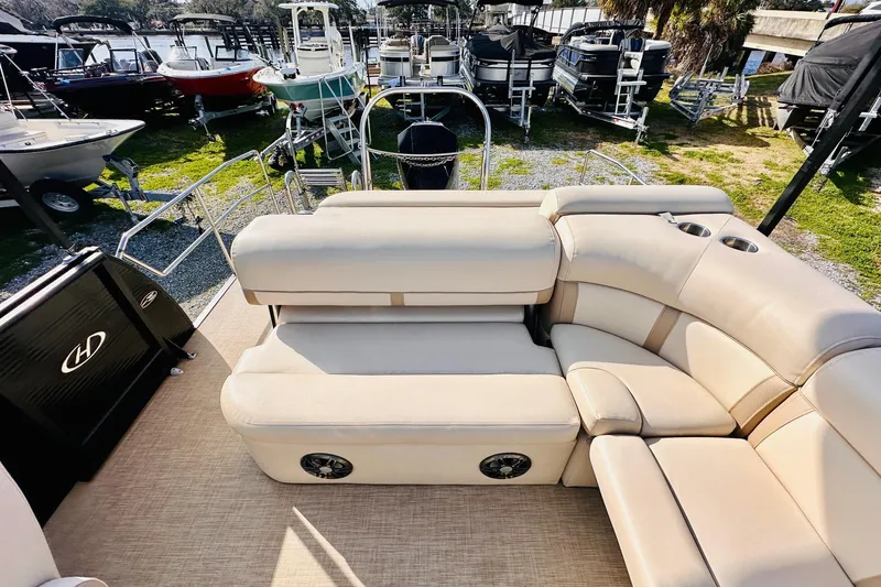 Slide: The Image of 2019 Harris Cruiser 250 pontoon boat with beige seating and cup holders, docked near other boats. - 16