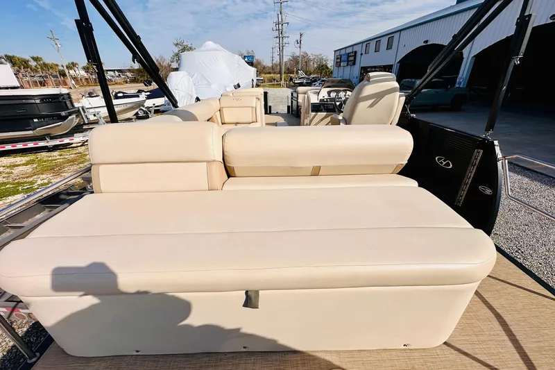 Slide: The Image of 2019 Harris Cruiser 250 boat with beige seating, docked outdoors under a clear sky. - 18