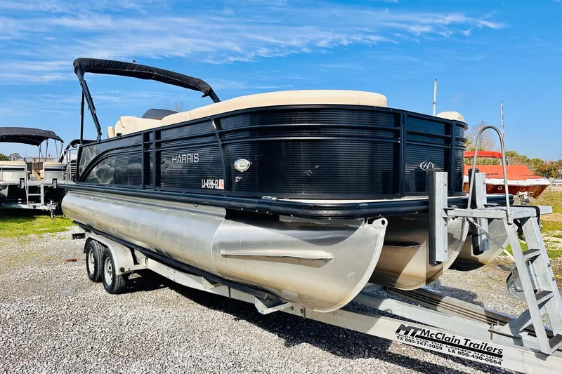 Slide: The Image of 2019 Harris Cruiser 250 pontoon boat on a trailer, parked outdoors under a clear blue sky. - 4