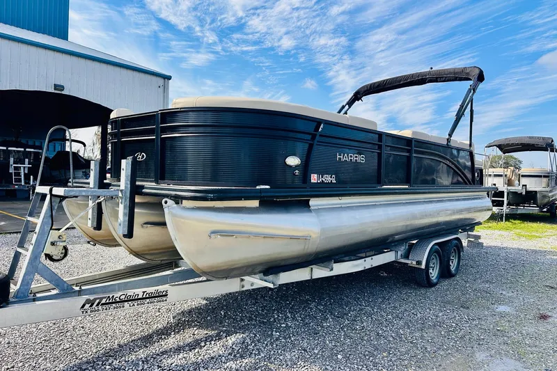 Slide: The Image of 2019 Harris Cruiser 250 pontoon boat on trailer, parked outside a building. - 5