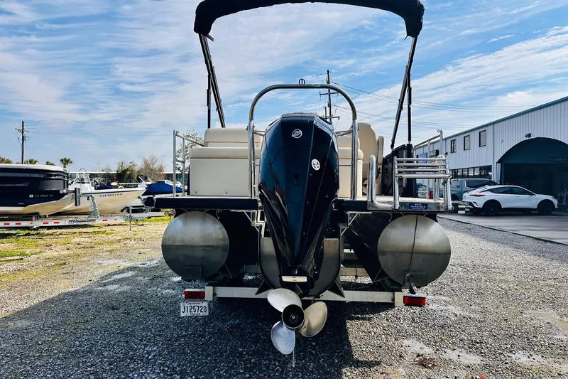 Slide: The Image of 2019 Harris Cruiser 250 pontoon boat with outboard motor, parked on gravel lot. - 7