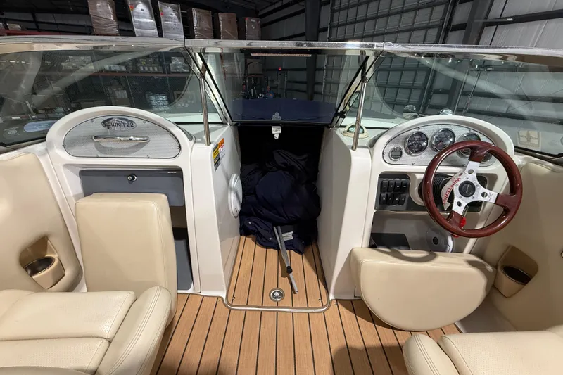 Slide: The Image of 2005 Chris-Craft Launch 22 boat interior with beige seating and wooden steering wheel. - 14