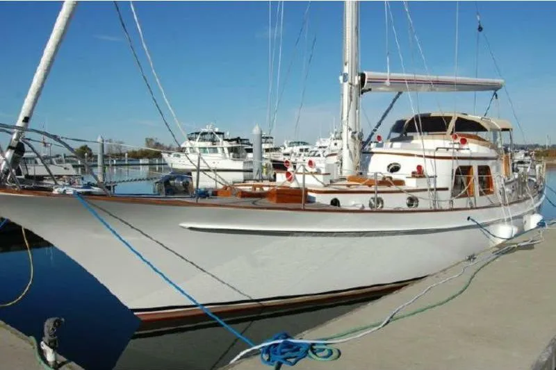 Slide: The Image of 1972 Rhodes 53 Motorsailor docked at marina under clear blue sky. - 0