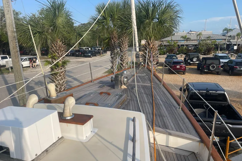 Slide: The Image of 1972 Rhodes 53 Motorsailor docked, surrounded by palm trees and parked vehicles. - 12