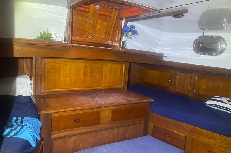 Slide: The Image of Cozy wooden cabin interior of 1972 Rhodes 53 Motorsailor with blue bedding and porthole. - 34