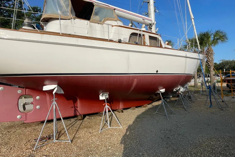 Slide: The Image of 1972 Rhodes 53 Motorsailor on stands, white and red hull, outdoor setting. - 5