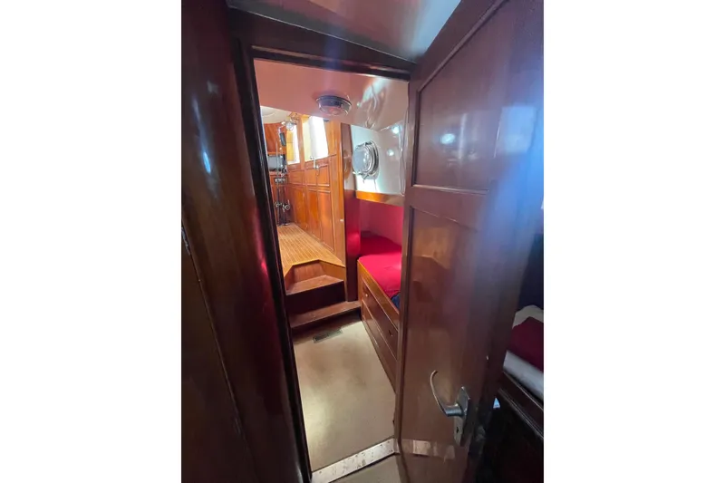 Slide: The Image of Interior view of 1972 Rhodes 53 Motorsailor with wooden paneling and red bedding. - 69
