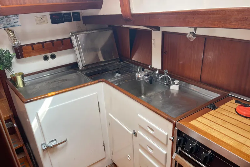Slide: The Image of 1972 Rhodes 53 Motorsailor galley with stainless steel sink, stove, and wooden cabinetry. - 70