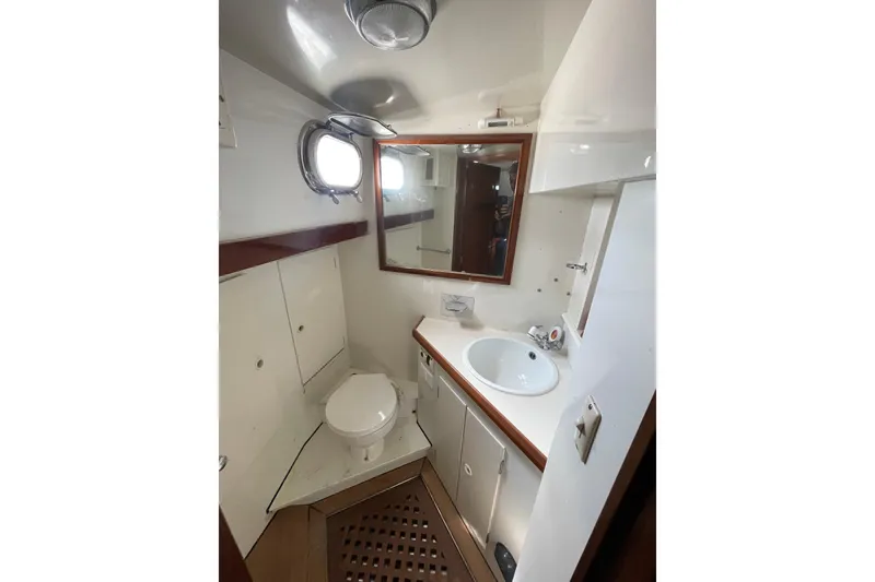 Slide: The Image of 1972 Rhodes 53 Motorsailor bathroom with sink, toilet, mirror, and porthole window. - 75