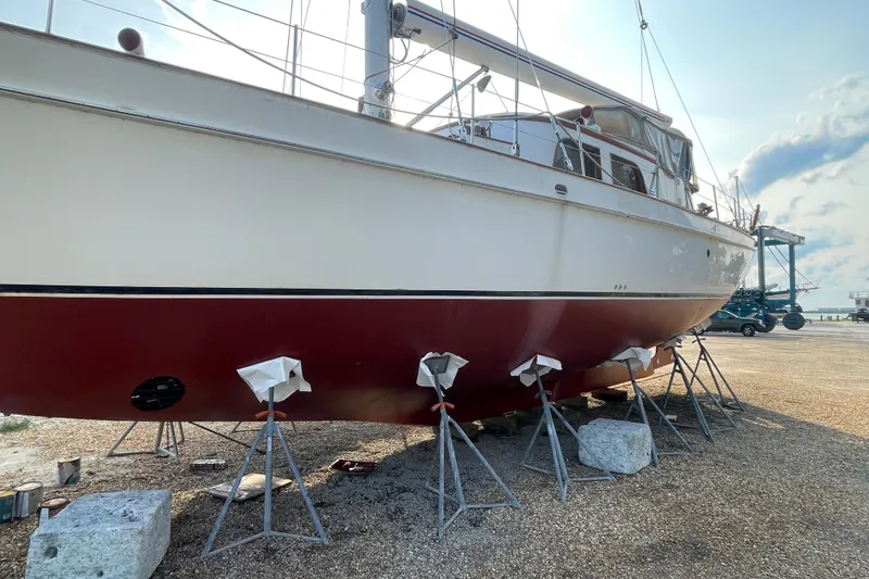 Slide: The Image of 1972 Rhodes 53 Motorsailor on stands, red hull, outdoor setting. - 8