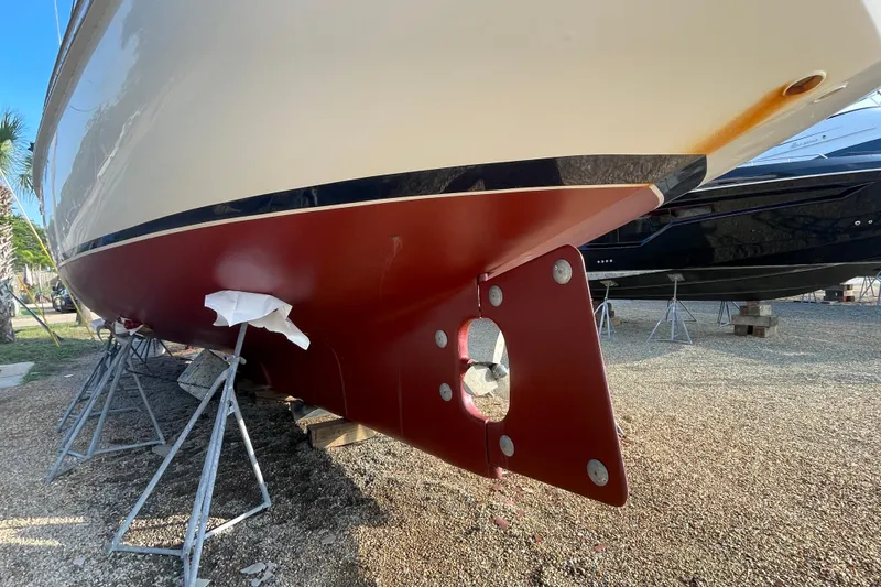 Slide: The Image of 1972 Rhodes 53 Motorsailor hull on stands, showcasing red and white paintwork. - 9