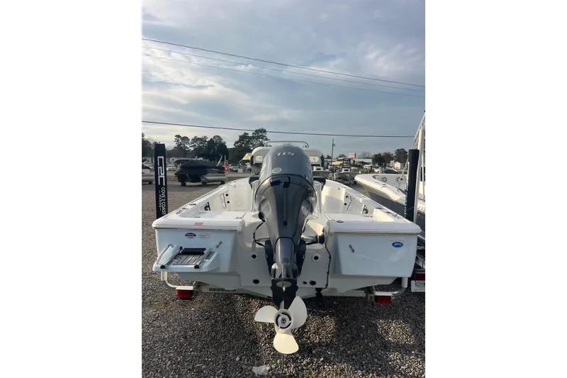 Slide: The Image of 2026 Tidewater 1910 Bay Max boat with outboard motor, parked on gravel lot. - 10