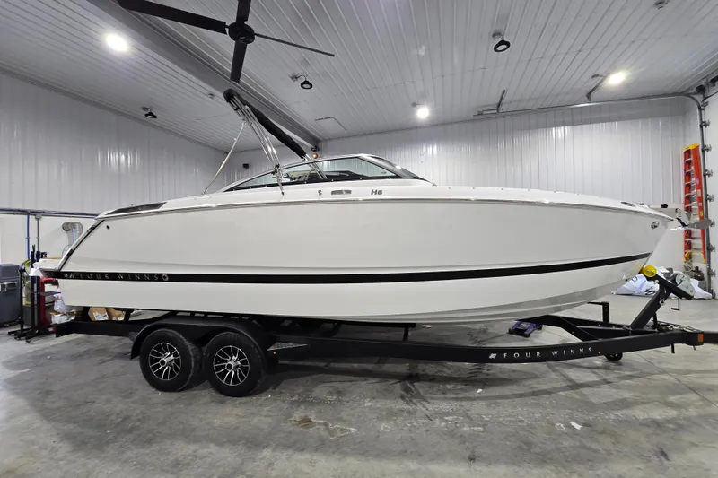 The Image of 2026 Four Winns H6 boat on trailer in indoor storage facility. - 1
