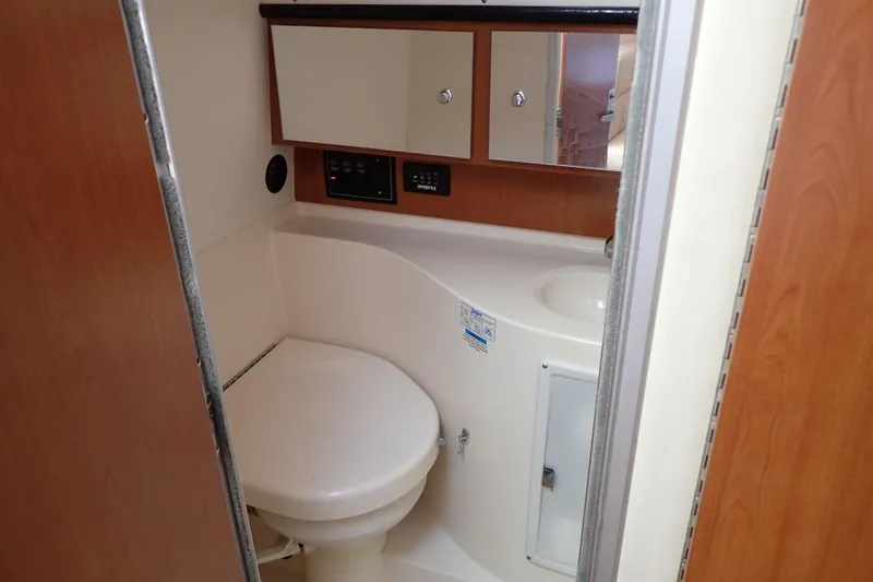 Slide: The Image of 2006 Wellcraft 330 Coastal boat bathroom with toilet, sink, and storage cabinets. - 102