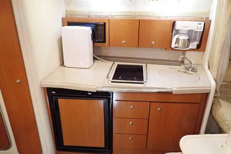 Slide: The Image of 2006 Wellcraft 330 Coastal boat kitchen with appliances, wooden cabinets, and compact design. - 33