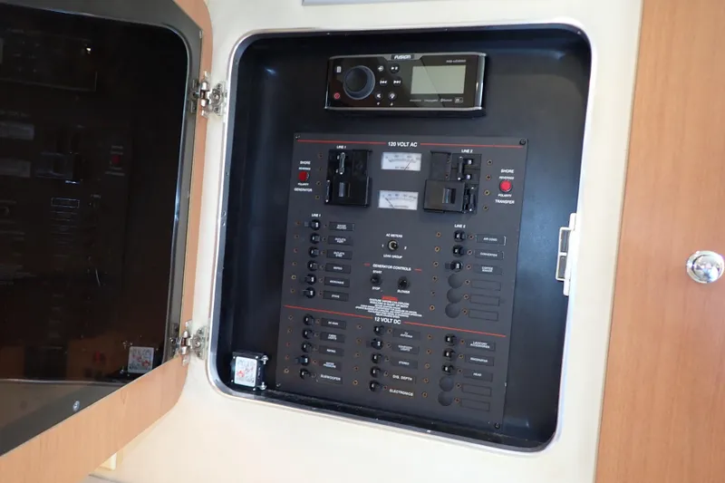 Slide: The Image of Electrical control panel inside 2006 Wellcraft 330 Coastal boat, featuring various switches and meters. - 77