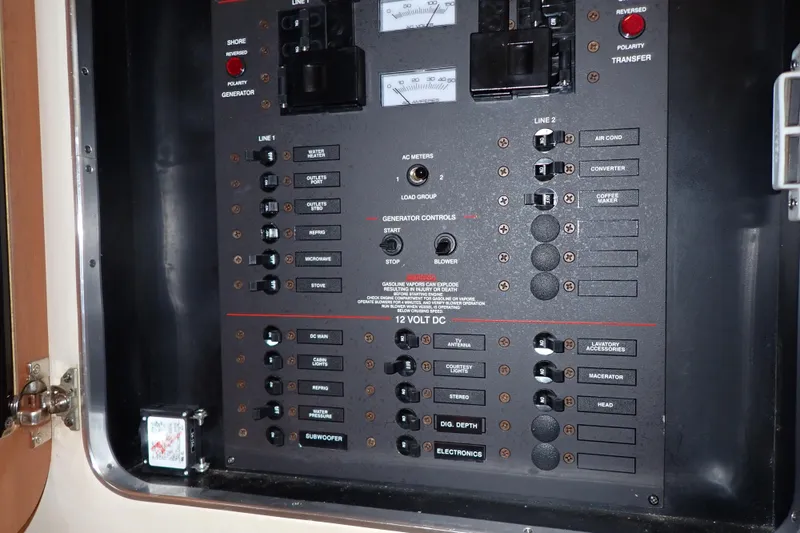 Slide: The Image of Electrical control panel on a 2006 Wellcraft 330 Coastal boat, featuring various switches and meters. - 79