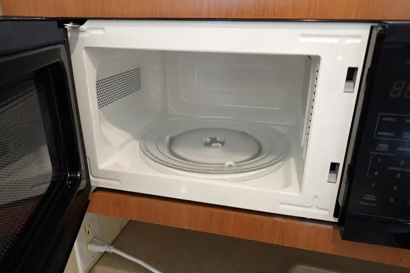 Slide: The Image of Open microwave oven with glass turntable inside, set in a wooden cabinet. - 82