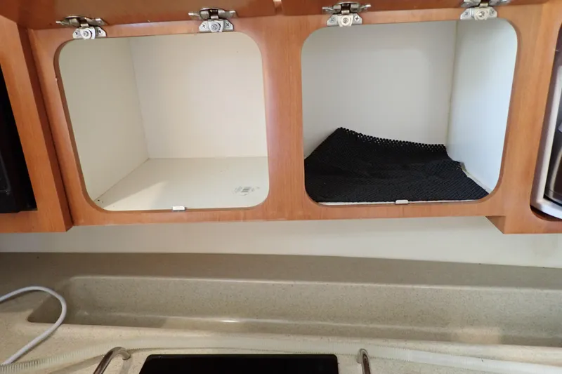 Slide: The Image of Open wooden cabinets in a 2006 Wellcraft 330 Coastal boat kitchen area. - 84