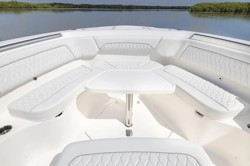 Slide: The Image of Manufacturer Provided Image: 2026 Pursuit S 388 Sport boat interior with white cushioned seating and table on calm water. - 6
