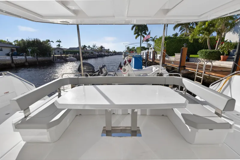 Slide: The Image of 2024 Leopard 46 Powercat yacht with outdoor seating, docked by a scenic waterfront. - 11