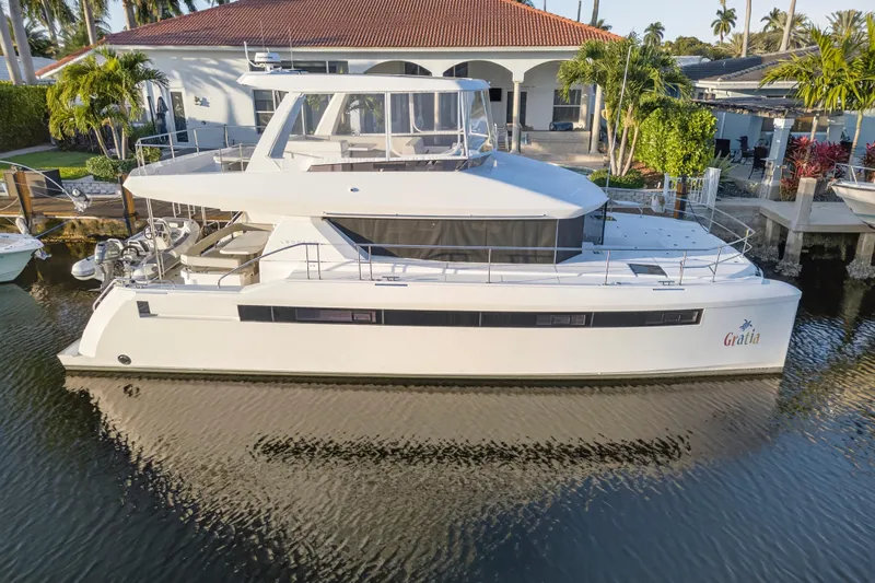 Slide: The Image of 2024 Leopard 46 Powercat yacht docked by a waterfront home, surrounded by tropical greenery. - 110