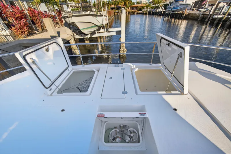 Slide: The Image of 2024 Leopard 46 Powercat deck with open storage compartments, docked by the water. - 99