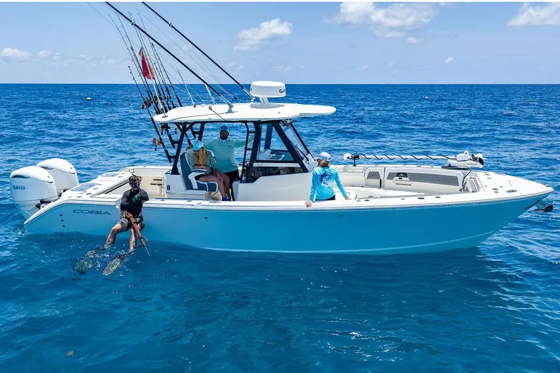 Slide: The Image of Manufacturer Provided Image: 2026 Cobia 305 Center Console boat on open ocean with people fishing and diving. - 1
