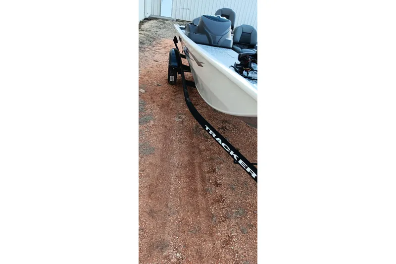 Slide: The Image of 2026 Tracker Pro 170 boat on trailer, parked on gravel near a building. - 2