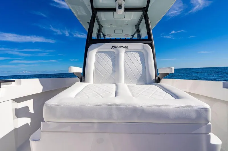 Slide: The Image of 2026 Reef Runner 280 boat with white cushioned seating, ocean backdrop, and clear blue sky. - 29