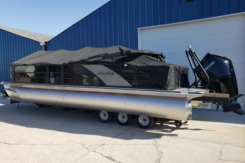 Slide: The Image of 2026 Bentley Pontoons Elite 253 Swingback Bench with cover, parked on trailer. - 4