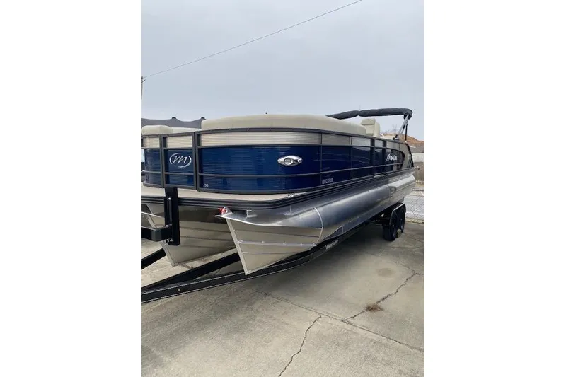 Slide: The Image of 2026 Manitou 25 Encore SL SHP pontoon boat on trailer, blue and beige design. - 8