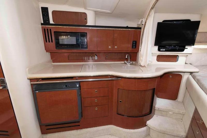 Slide: The Image of 2002 Sea Ray Sundancer 310 interior with kitchenette, featuring microwave, sink, and TV. - 9