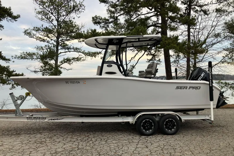 The Image of 2022 Sea Pro 239 Deep V CC boat on trailer, parked near trees and lake. - 1