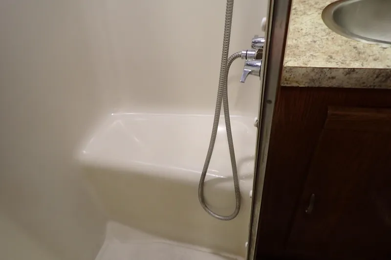 Slide: The Image of 1988 Mainship boat bathroom with shower, sink, and wooden cabinet. - 100