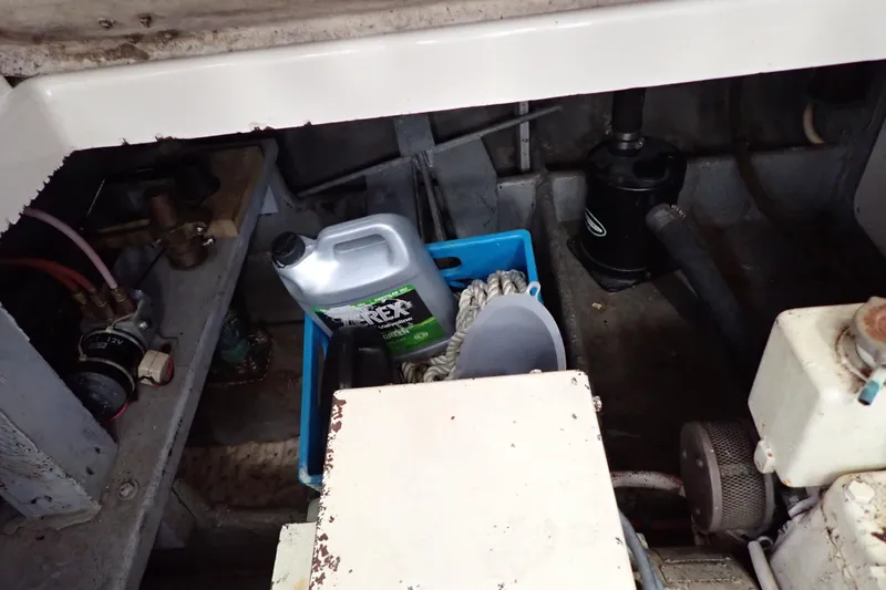 Slide: The Image of 1988 Mainship engine compartment with oil container, ropes, and mechanical components. - 107