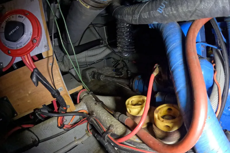 Slide: The Image of 1988 Mainship engine compartment with wiring, hoses, and mechanical components. - 115