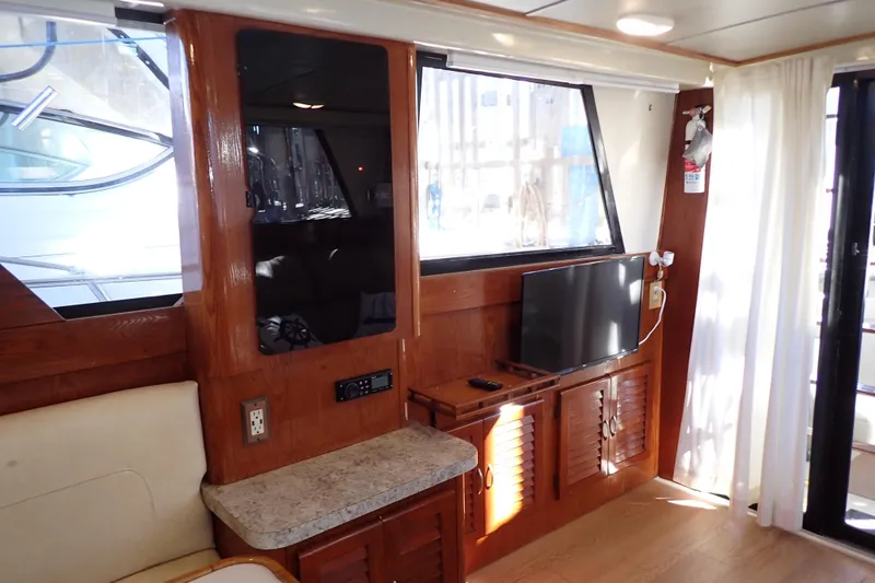 Slide: The Image of 1988 Mainship boat interior with wood paneling, TV, and seating area. - 14