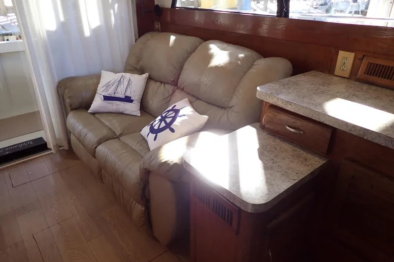 Slide: The Image of 1988 Mainship interior with beige sofa, nautical-themed pillows, and wooden cabinetry. - 16