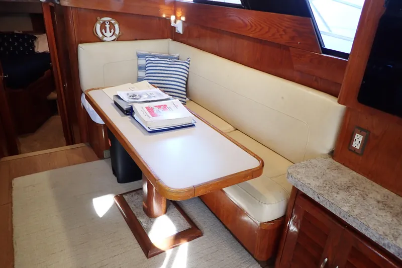 Slide: The Image of 1988 Mainship interior with dining area, wooden table, and cushioned seating. - 17