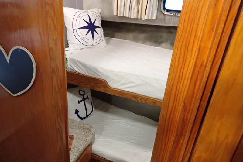 Slide: The Image of Cozy 1988 Mainship cabin with nautical-themed bunk beds and wooden interior. - 18