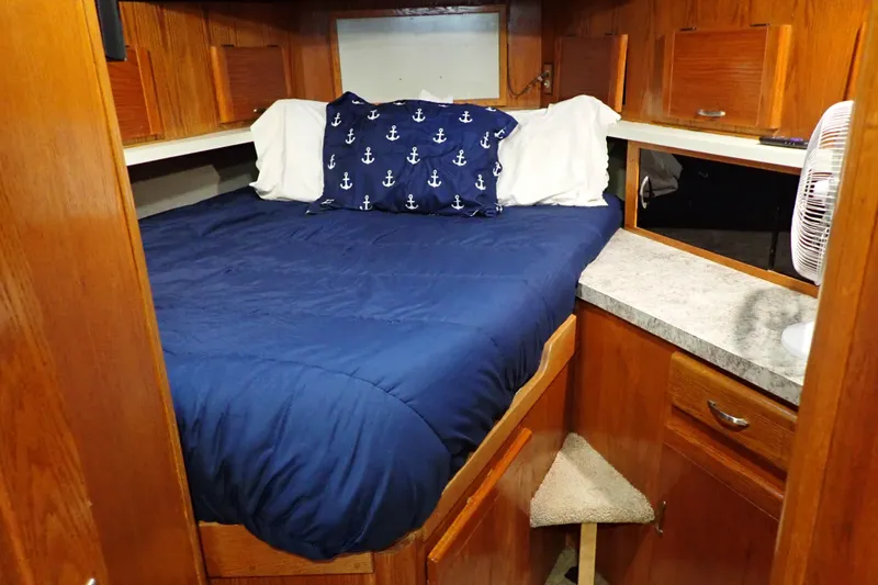 Slide: The Image of 1988 Mainship boat cabin with blue bedding, anchor-themed pillow, and wooden cabinetry. - 19