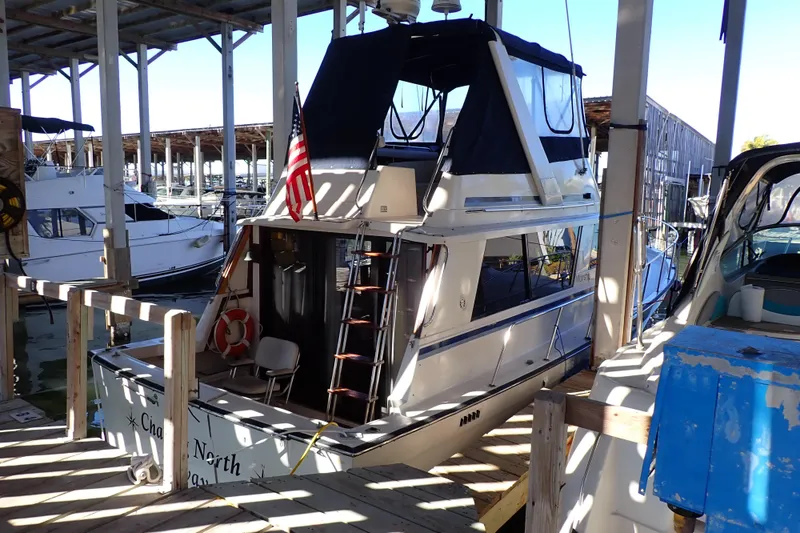 Slide: The Image of 1988 Mainship boat docked in a marina, featuring an American flag and covered upper deck. - 2